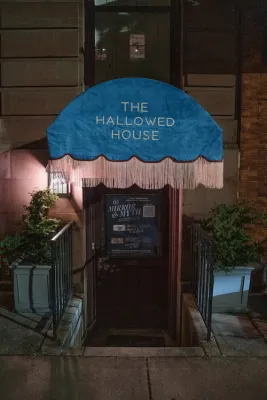 blue awning over door with steps down, awning says The Hallowed House