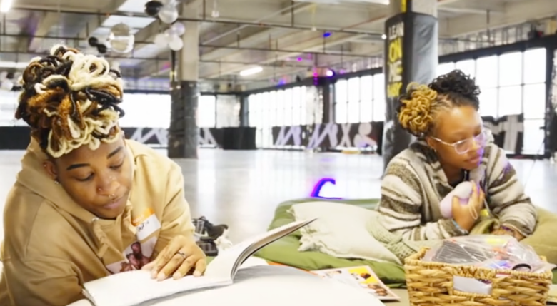 two people lying on stomachs and pillows looking at books