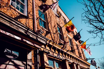 photo of red brick building shot from the ground looking up, with row of flags, and blue sky behind it