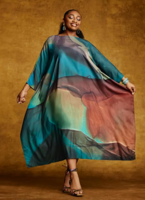 Woman in colorful flowing dress, smiles holding side of dress out to side