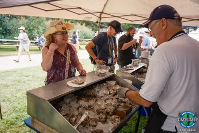 woman in straw hat buying food from an outdoor vendor under a tent cover
