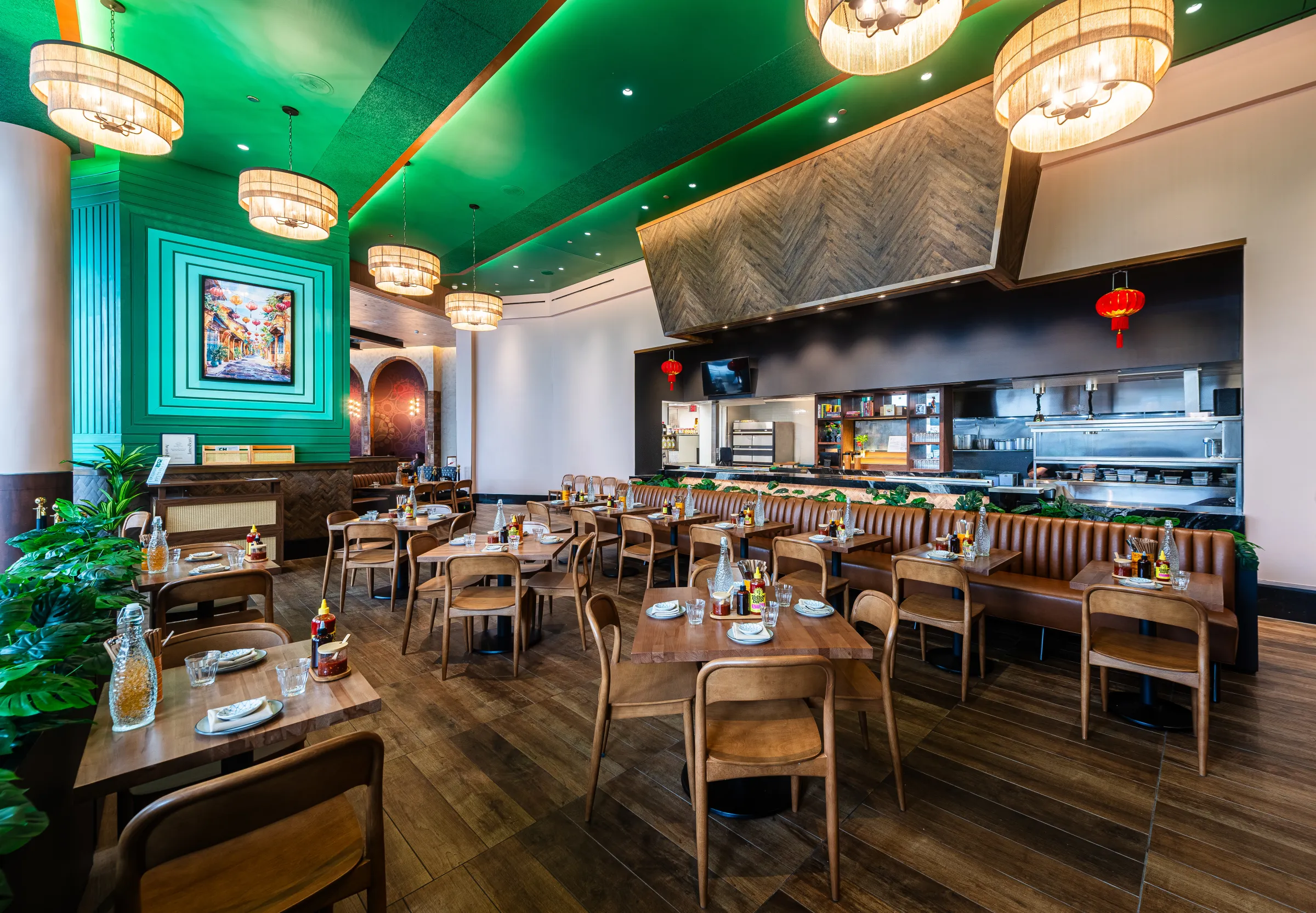 A jade-green ceiling oversees a sleek dining room full of neutral tones, wood, and leafy plants.