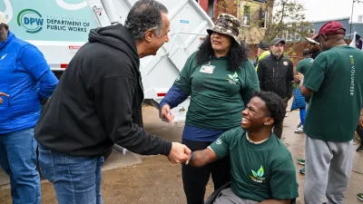 group of 3 people smiling at each other, 2 in green volunteer shirts at cleanup event