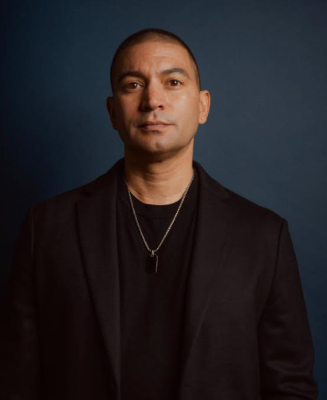 headshot of man in dark shirt looking at camera