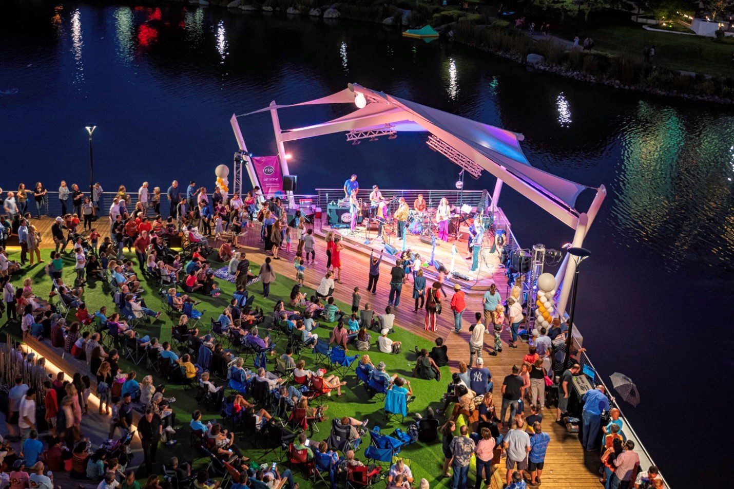 rio lakefront, people sitting on lawn chairs and looking at the stage while a band plays