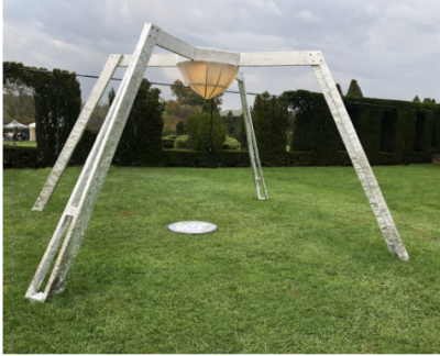 large sculpture on grass of metal with four pointed legs