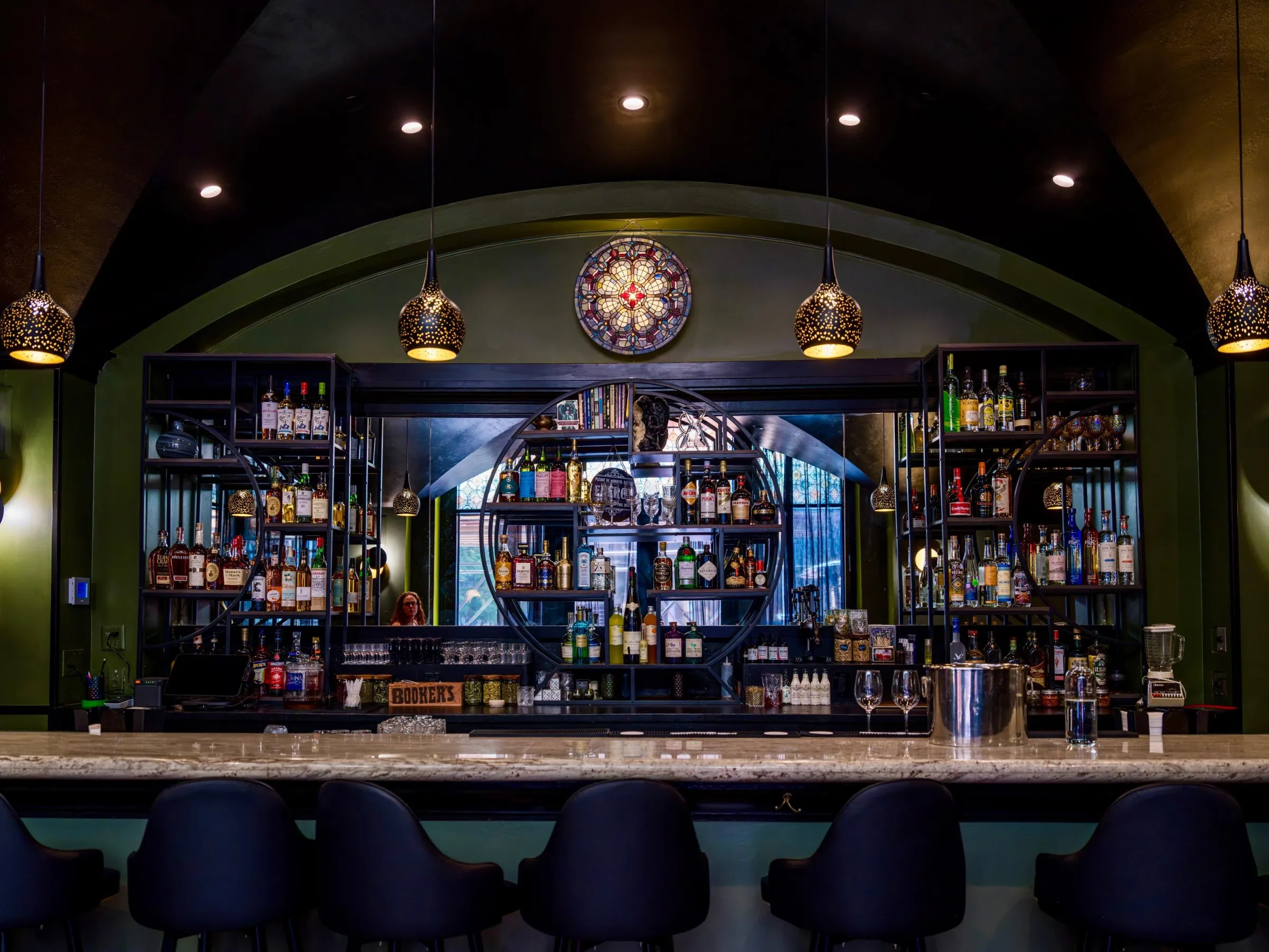 The veined stone bar is topped off with black metal and stained glass.
