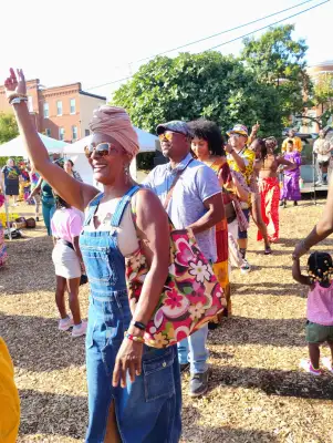 people standing in a line, front woman with hand in the air, all smiling