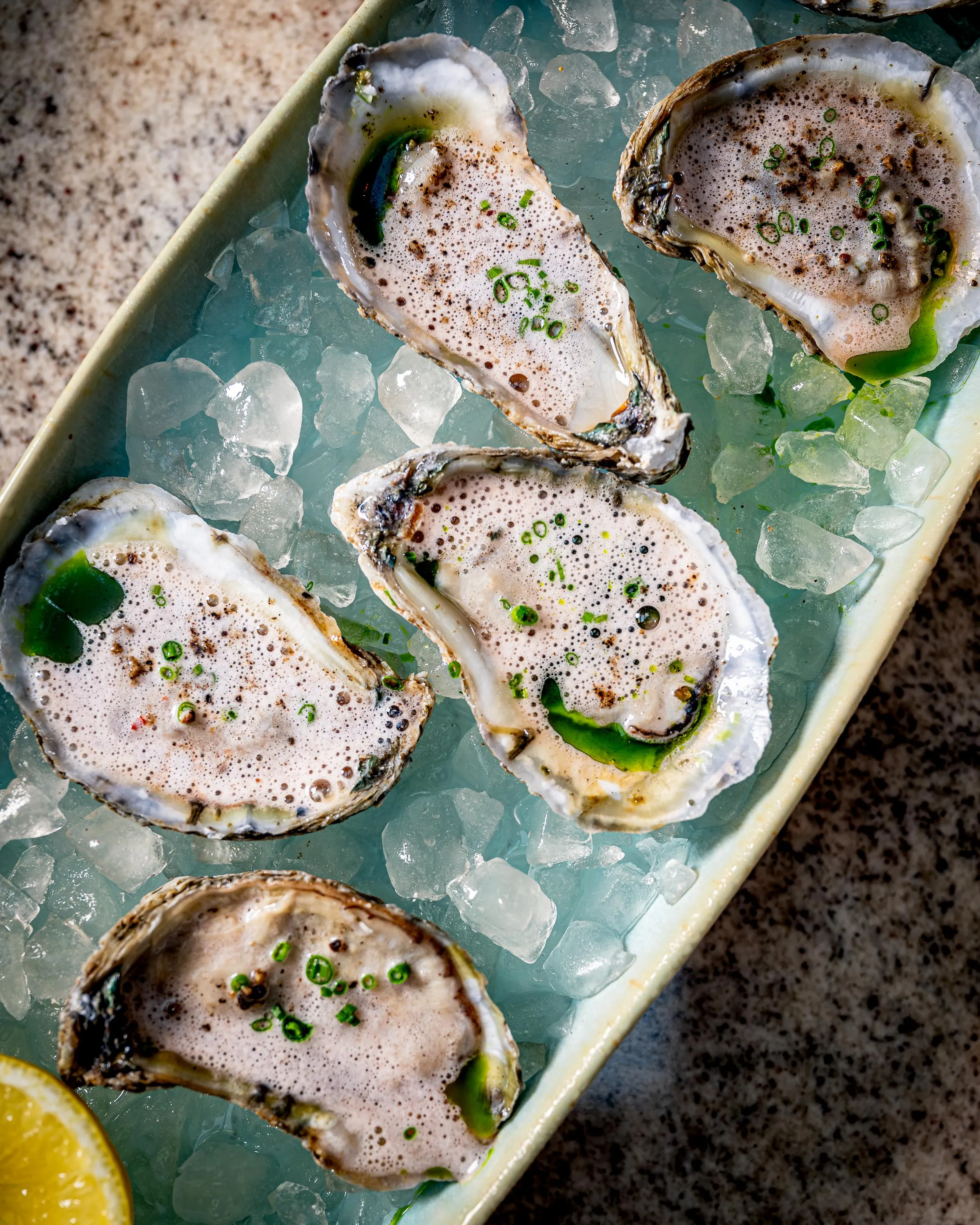 Fresh oysters adorned with grapefruit mignonette bubbles.