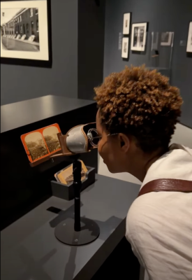 a woman looks into a viewfinder to study an old dagguereotype