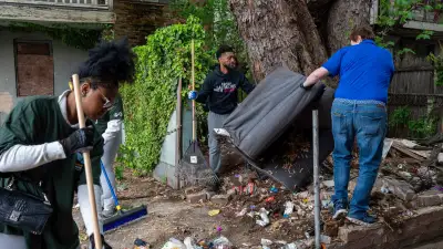 3 people cleaning up trash in an alley